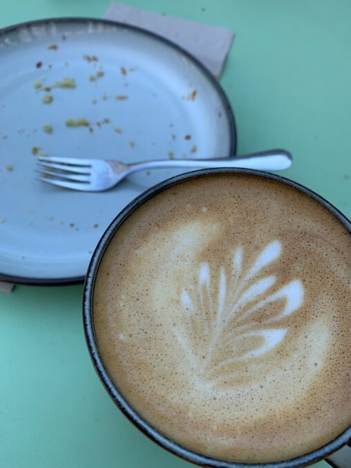 A cup of coffee and an empty plate of cake.