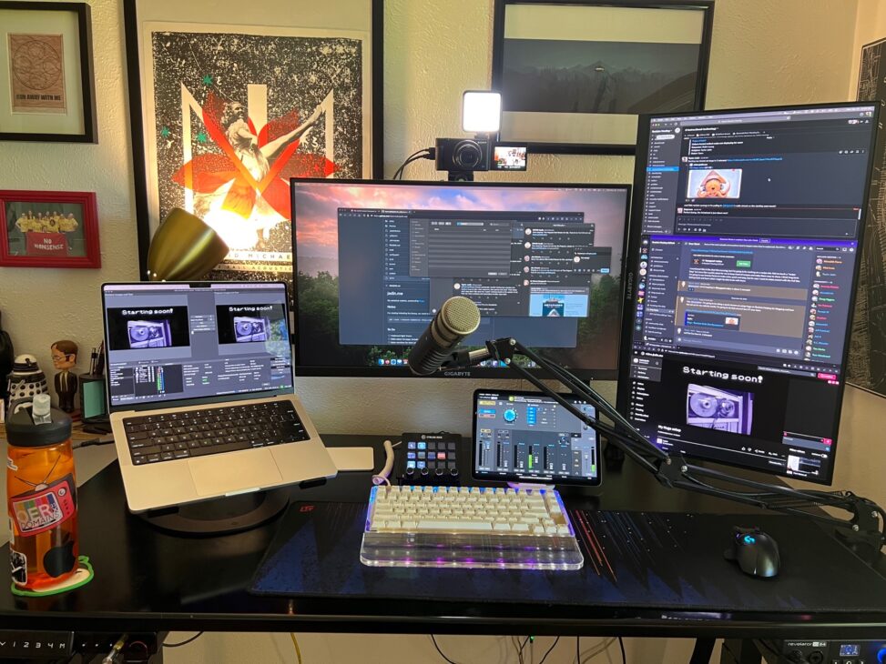 A desk with a laptop, and two external monitors, and ipad and elgato stream deck